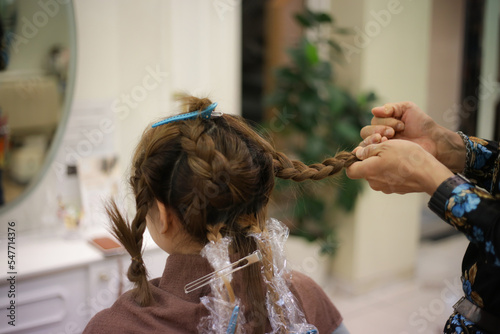 女性の髪を結ぶ男性美容師