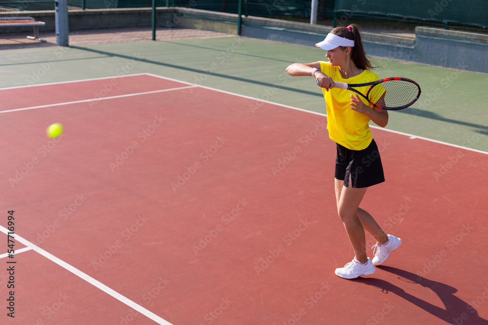 Professional equipped female tennis player beating hard the tennis ball with racquet.