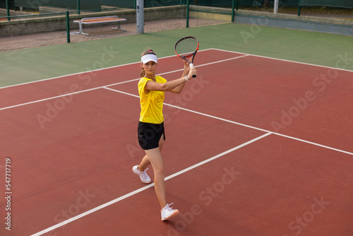 Professional equipped female tennis player beating hard the tennis ball with racquet. © ty
