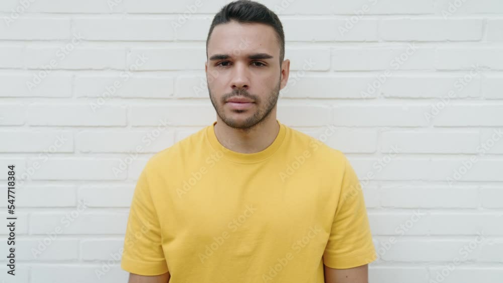 Young hispanic man doing negative sign with thumbs down over isolated white background Young hispanic man doing negative sign with thumbs down over isolated white background