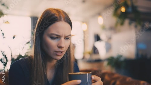 Young woman trying too hot coffee, breakfast in cafeteria, cafe visitor