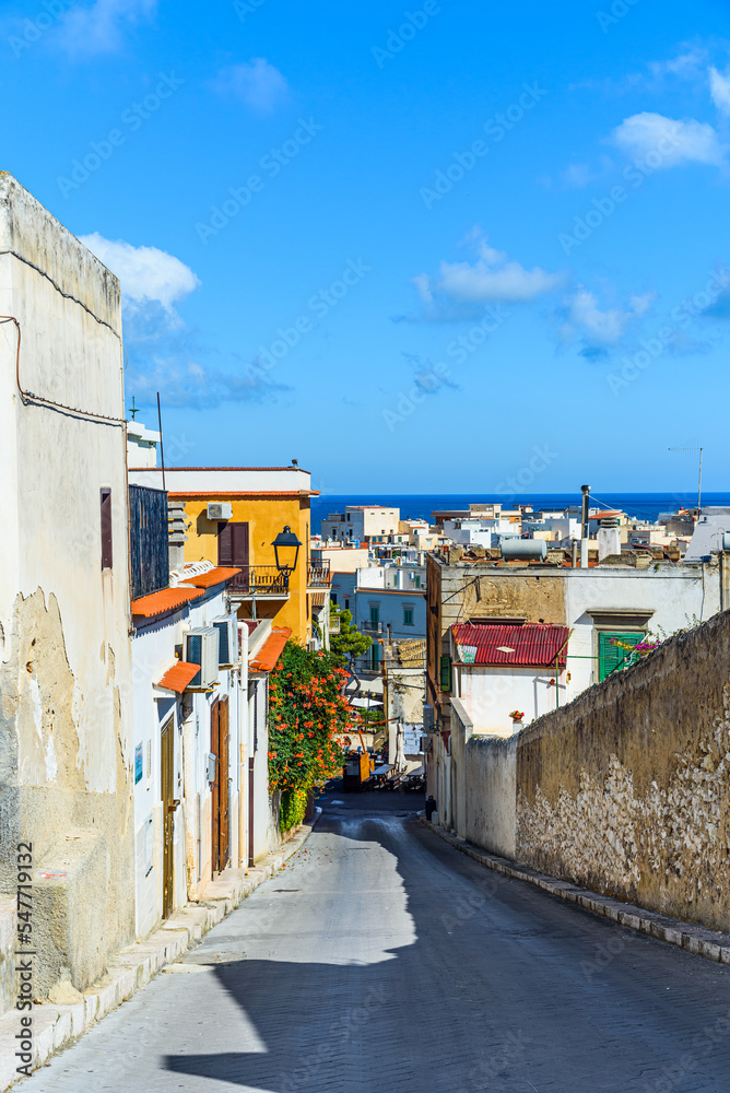 Vieste, Italy. View of a characteristic narrow street in the historic center of the town, near the Aragonese Castle, on a summer day. Vertical image. September 5, 2022.