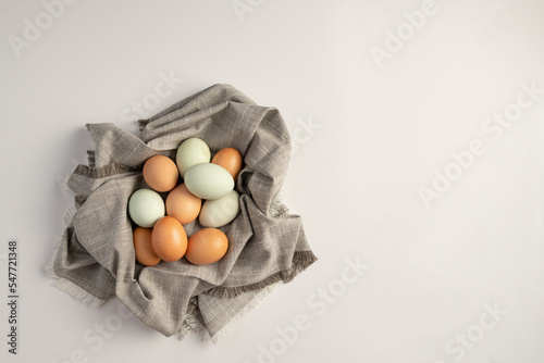 Pastel organic raw chicken eggs wrapped in a towel with copy space