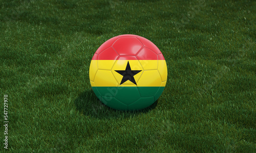 Soccer ball with Ghana flag colors at a stadium on green grasses background.