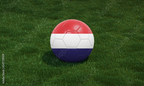 Soccer ball with Netherlands flag colors at a stadium on green grasses background.
