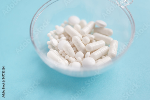 Scattered white pills on blue table. Mock up for special offers as advertising, web background or other ideas. Medical, pharmacy and healthcare concept. Copy space. Empty place for text or logo