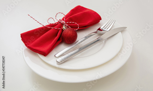 Christmas Holiday table setting. Silver Cutlery and red napkin on white plate