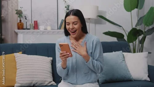 Wallpaper Mural Wonder happy young woman sitting on a blue sofa and using a smartphone smiling in a modern room. Tapping, scrolling. Slow motion Torontodigital.ca