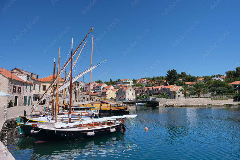 Sailing boats on marina in Hvar town harbor. Harbour in Hvar island, Croatia, Europe on a bright sunny day in Summer. Blue sky and calm sea. Hvar town with traditional Dalmatian architecture.