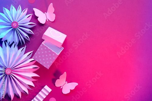 Birthday party decor border. Paper fans, butterflies, flowers. Flat lay with Spring ornaments, decorations, gift box on vibrant magenta background. Birthday, anniversary celebration with copy-space. © tilialucida