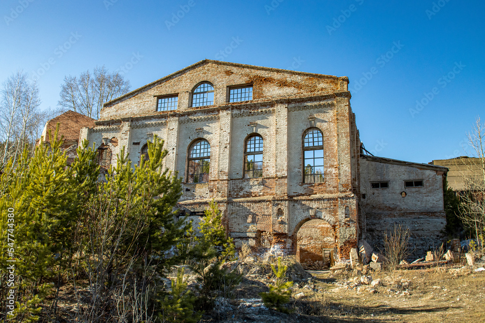 The preserved facade of an old ruined brick industrial building against the blue sky