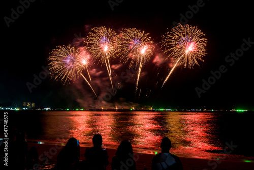 Amazing beautiful colorful fireworks display on celebration night, showing on the sea beach with multi color of reflection on water	 photo