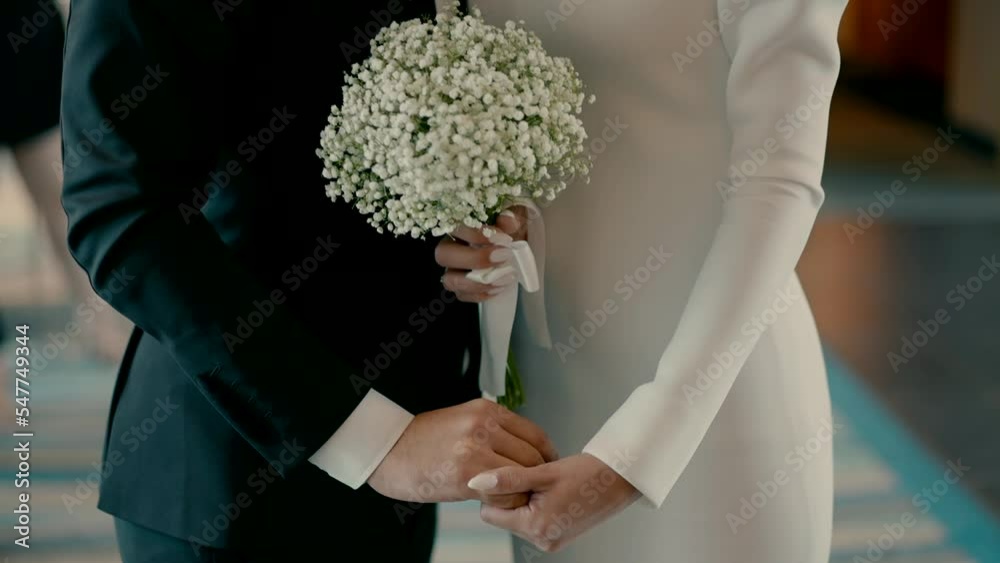 A bride and groom stand together and hold each other's hands. Beautiful slow motion video shoot of a bride and groom on a wedding day. Hand in hand next to each other. A bride and groom stand together and hold each other's hands. Beautiful slow motion video shoot of a bride and groom on a wedding day. Hand in hand next to each other.