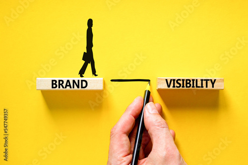 Brand visibility symbol. Concept words Brand visibility on wooden blocks. Beautiful yellow table yellow background. Businessman hand. Business branding and brand visibility concept. Copy space.