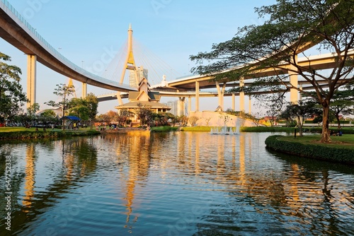 A museum by the lake in Lat Pho Park under Industrial Ring Road Bridge  or Bhumibol Bridge  in Bangkok  Thailand   Scenery of elevated highway interchange and bridge tower reflected on lake water