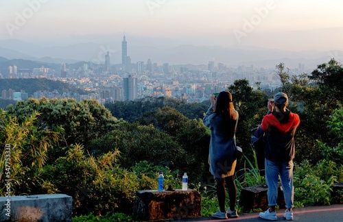 Tourists take photos of Taipei 101 Tower among skyscrapers in Xinyi Financial District & crowded buildings in Downtown area under beautiful sunset sky ~ Romantic scenery of Taipei City at sunset  © AaronPlayStation