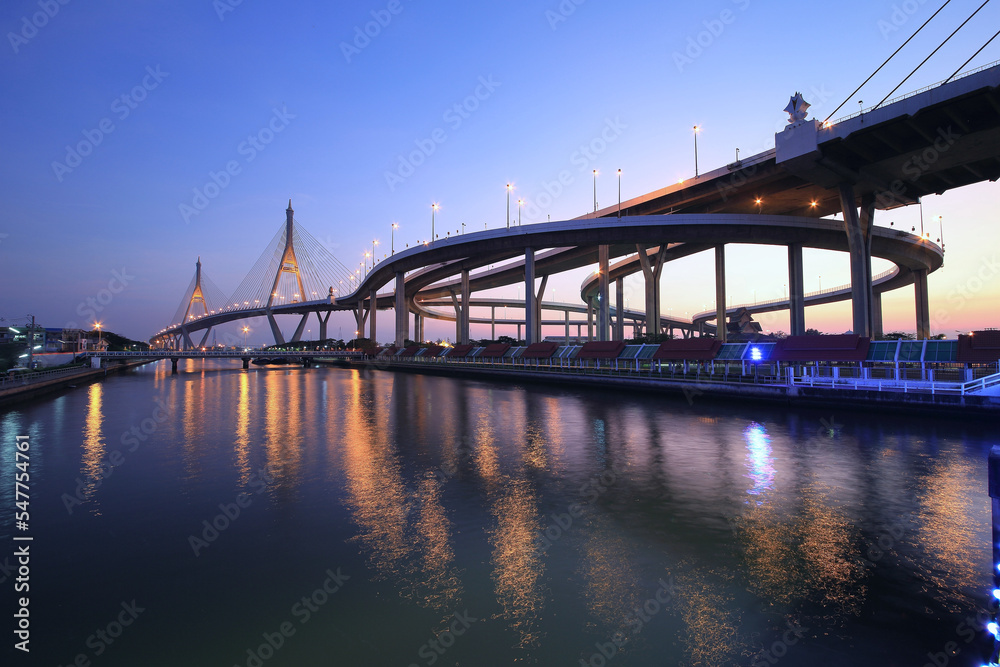 Night view of Bhumibol Suspension Bridge ( Industrial Ring Road ) over Chao Phraya River at dusk in Bangkok City Thailand, a beautiful landmark with reflections of lights on water in evening twilight