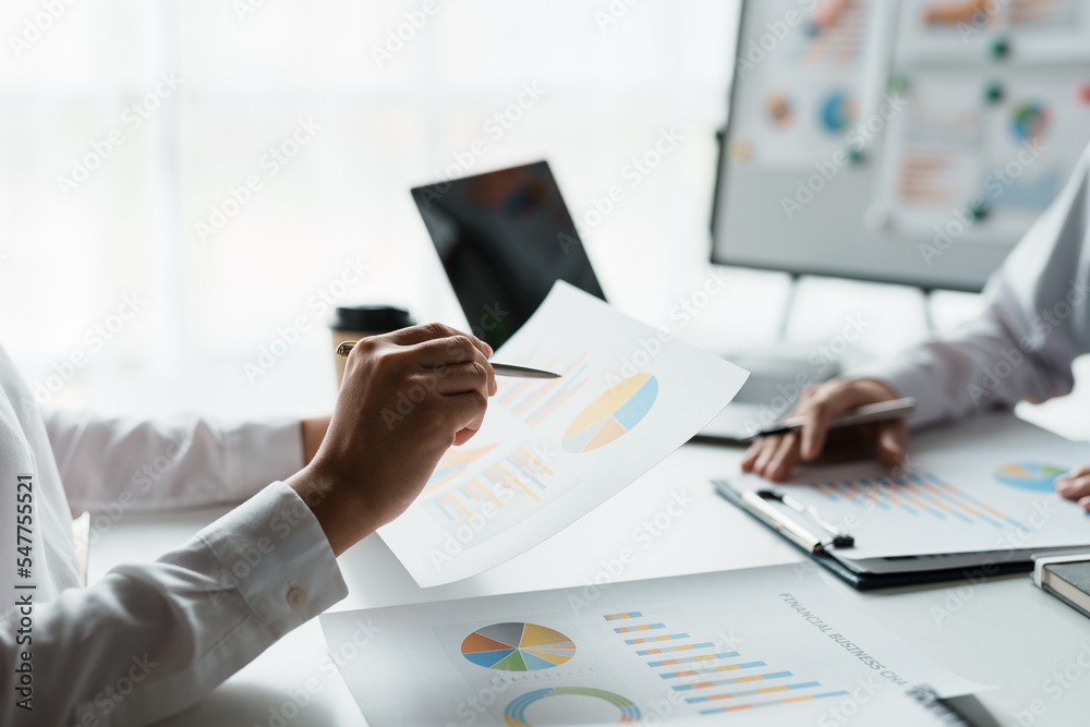 Two business people point to graphs and charts to analyze market data ...
