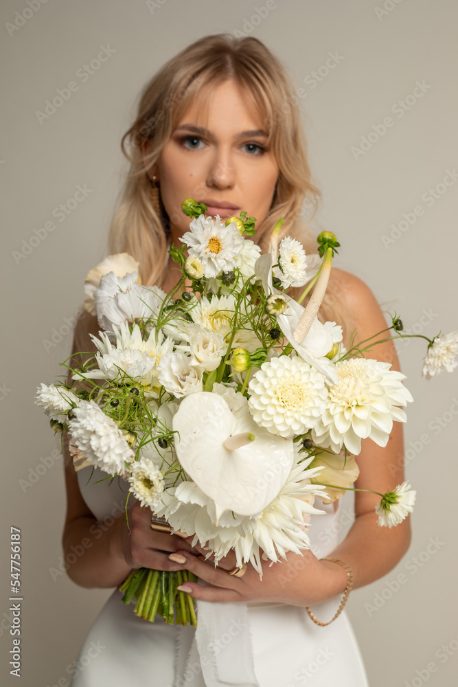 Vertical charming relaxed anticipating blond woman, bride in light white dress covered with big white bouquet of flowers Vertical charming relaxed anticipating blond woman, bride in light white dress covered with big white bouquet of flowers