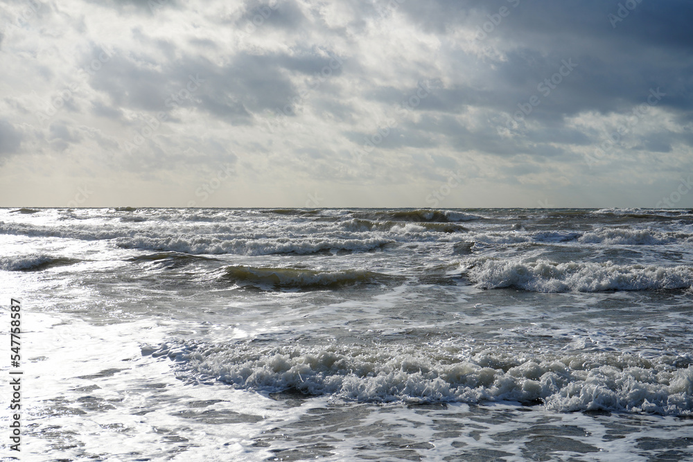 Waves crashing in the ocean with a cloudy sky