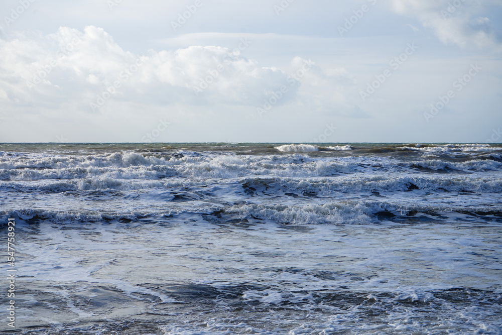 Waves crashing in the ocean with a cloudy sky