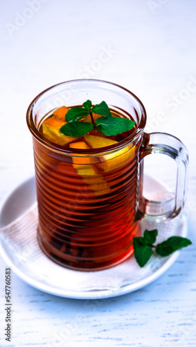 Pink fruit tea with mint leaves and lemon. Pink fruit tea in a glass cup.