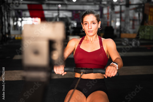 young caucasian woman doing sports with specialized machines in a large gym looking at camera