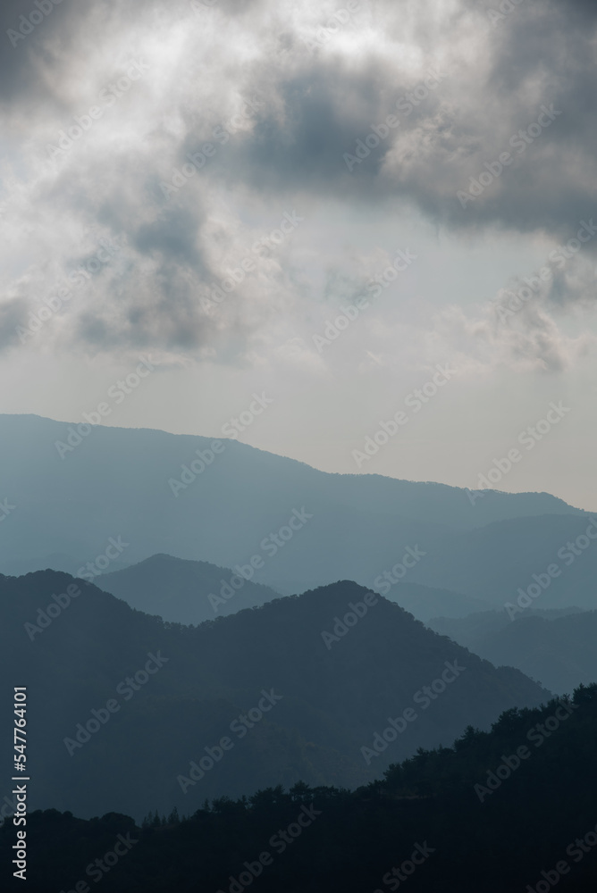 Mountain landscape with bright sun rays shining and cloudy sky in the morning.