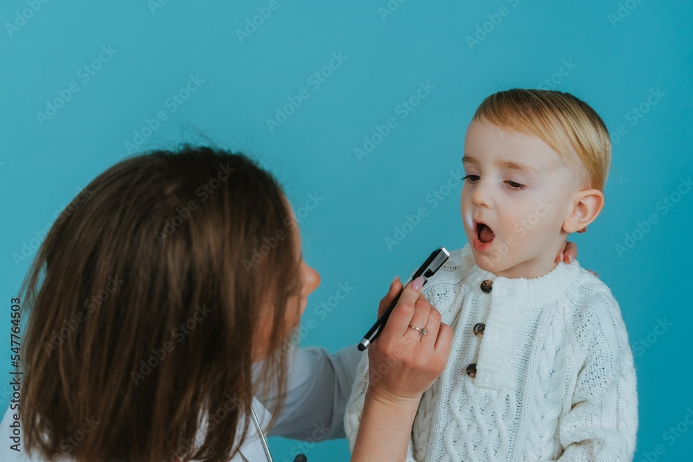 Woman doctor examining the throat of a little boy