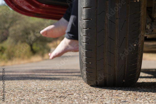 tire on road in summer with girl feet in background