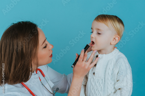 Woman doctor examining the throat of a little boy