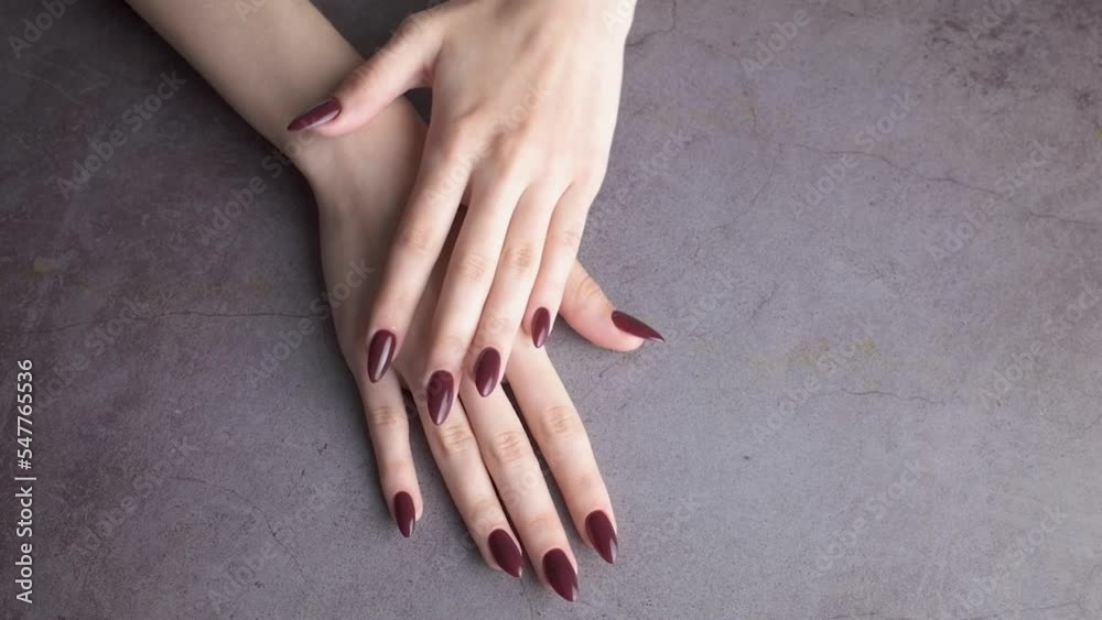 Beautiful hands of a young woman with dark red manicure on nails. 
