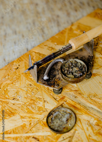 a soldering iron with a wooden handle with solder and rosin lies on a wooden board