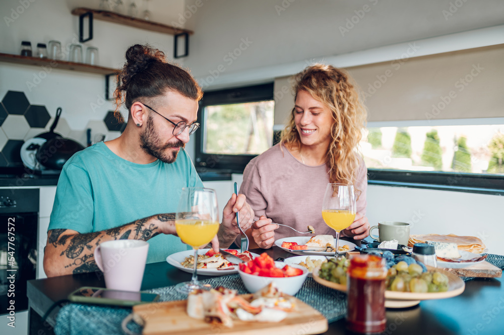 Couple eating breakfast together while sitting at table at home