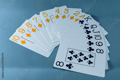 White card fan of diamonds and cross suits, orange and black, respectively, on a blue background.