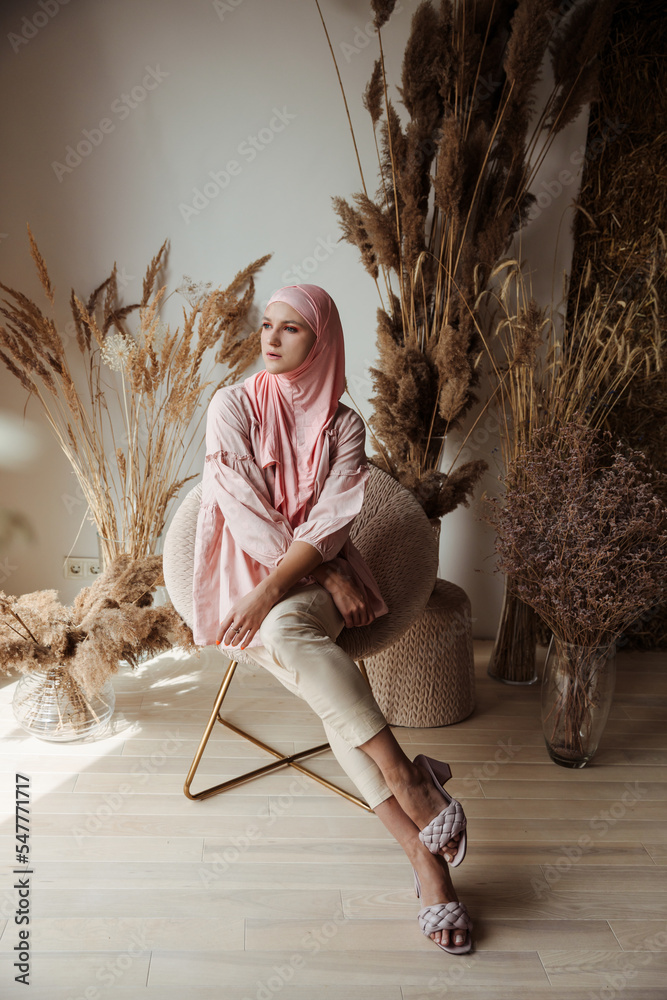 Beautiful muslim arabian woman wearing pink hijab sitting on the chair ...