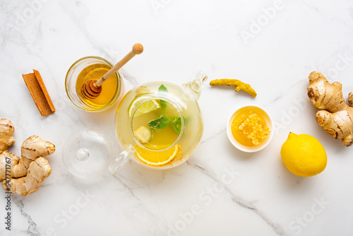 Winter ginger spice and fruits tea in teapot on marble surface top view
