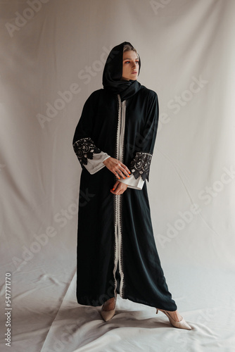 Beautiful muslim woman in traditional arabian abaya dress on gray background photo