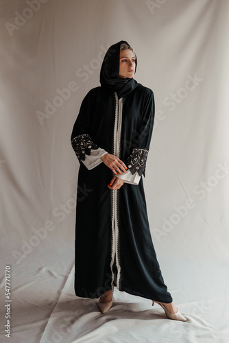 Beautiful muslim woman in traditional arabian abaya dress on gray background