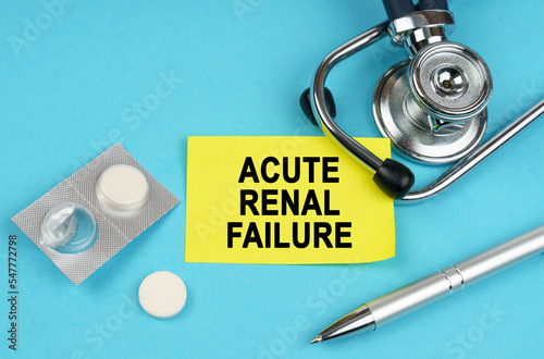 On a blue surface, a stethoscope, pills, a pen and a yellow sticker with the inscription - Acute renal failure photo