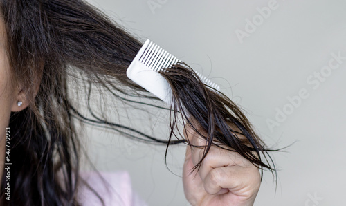 woman applying serum oil on wet hair with pipette or using white comb to disentangle isolated.healthy strong hair,growth stimulation stop fall shiny.top of head forehead lateral view.after pregnancy photo