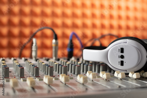 Sound record studio in audio mixing console. Music headphones near acoustic foam