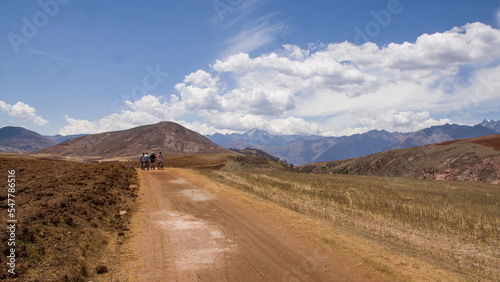 Dry andean landscape with dirt road near mountains and mountain bikers Cusco, Peru