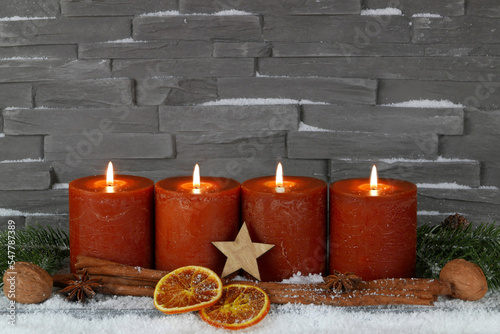 Fotoserie zur Adventszeit  Adventskerzen mit Zimtstangen und Orangenscheiben auf einer Baumscheibe dekoriert.