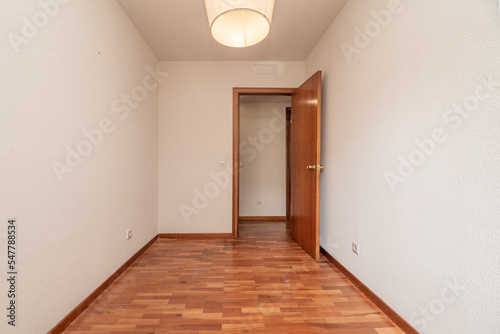 Empty living room with reddish parquet flooring with matching skirting and wooden doors