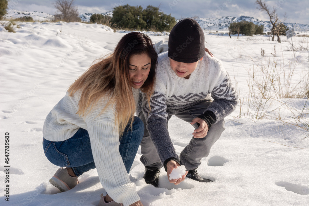 mother and son playing with snowballs in snowy field