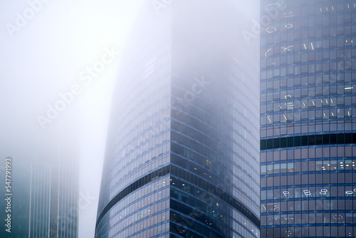 Windows of skyscrapers in the fog  background copy space. Metal structures with windows of a high-rise building in smog  close-up