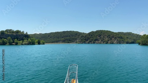 Stunning view from a sailing ship on the sea to the green mountains, turquoise deep sea and green rolling mountains,  panoramic tourist view closeup concept, ships stern against the blue sky 