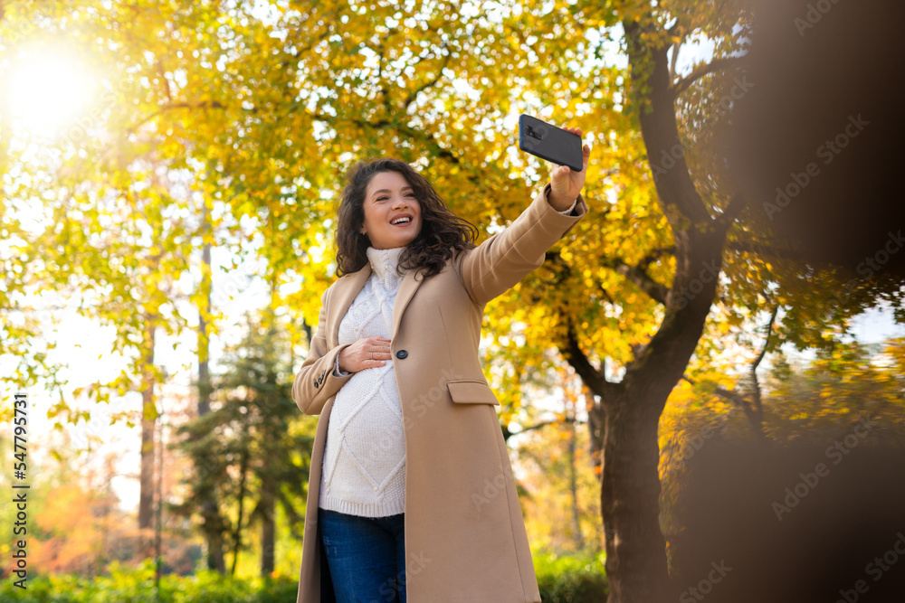 Pregnant woman taking photo in the park