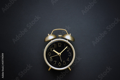 Golden vintage alarm clock on black background. Time concept. Selective focus, copy space